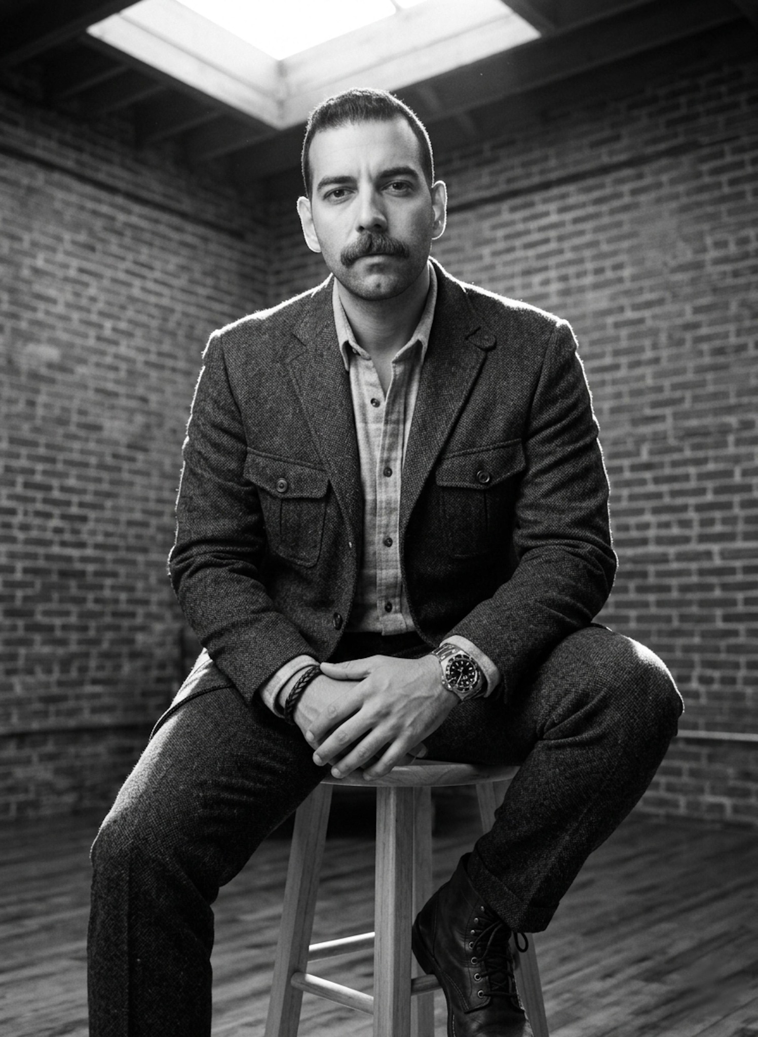 High-contrast black and white portrait in tweed with dramatic rim light in industrial studio