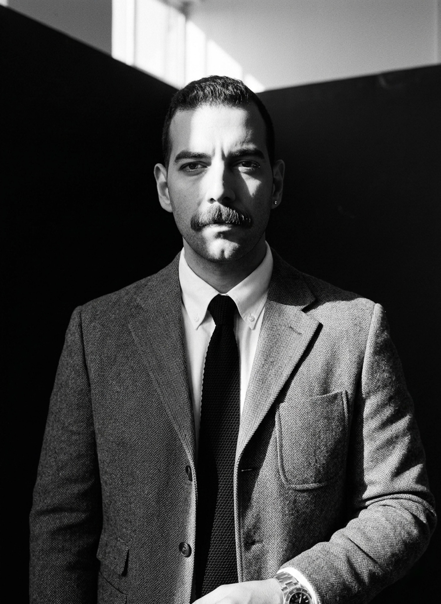 Person with piercing gaze in high-contrast black and white with half face in deep shadow