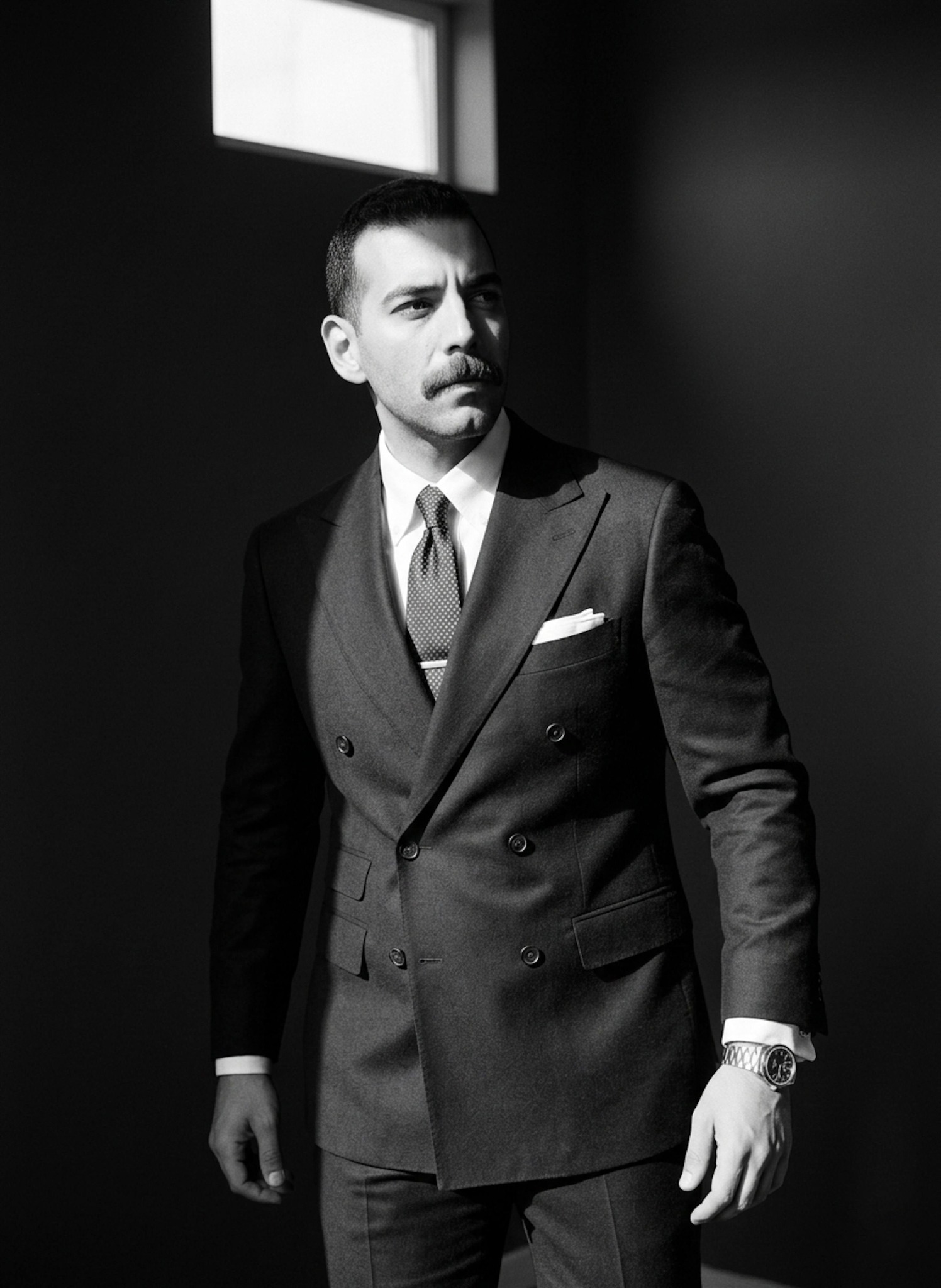 Person in suit turning sharply with narrow sunlight beam on face in high-contrast noir style