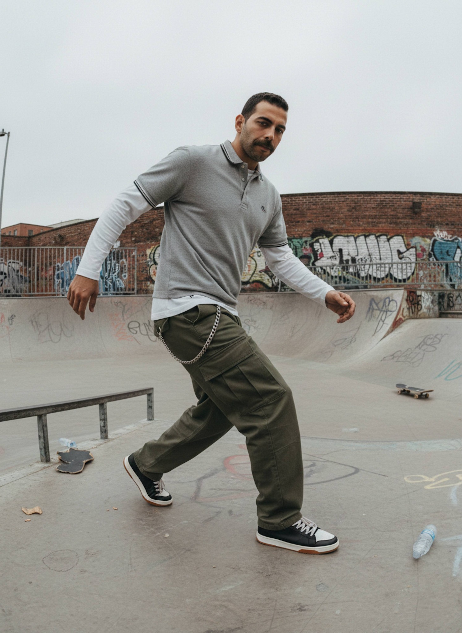 Person in layered polo and baggy cargo pants mid-skate in early 2000s urban skate park