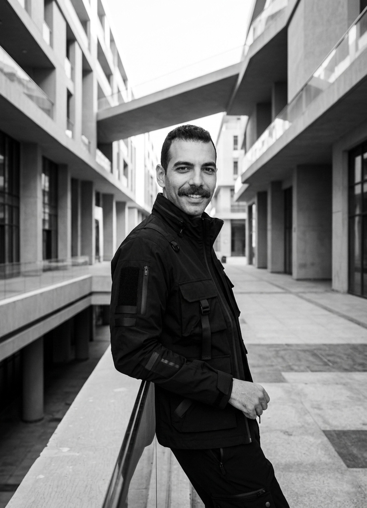 Person in structured techwear utility jacket at San Stefano Grand Plaza with clean architectural lines in black and white