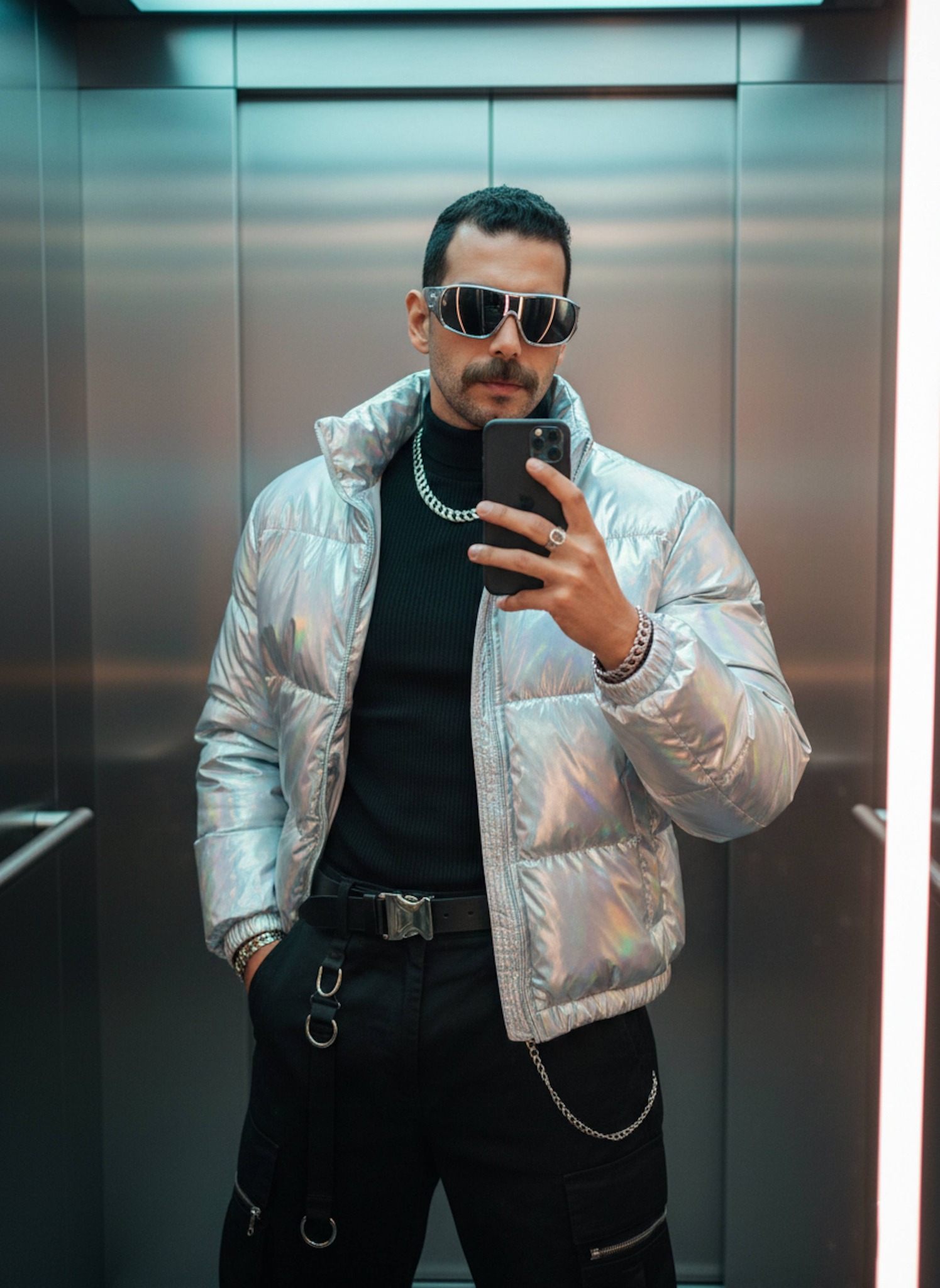Person in futuristic fashion taking a mirror selfie in a cyber-styled elevator with Y2K aesthetics