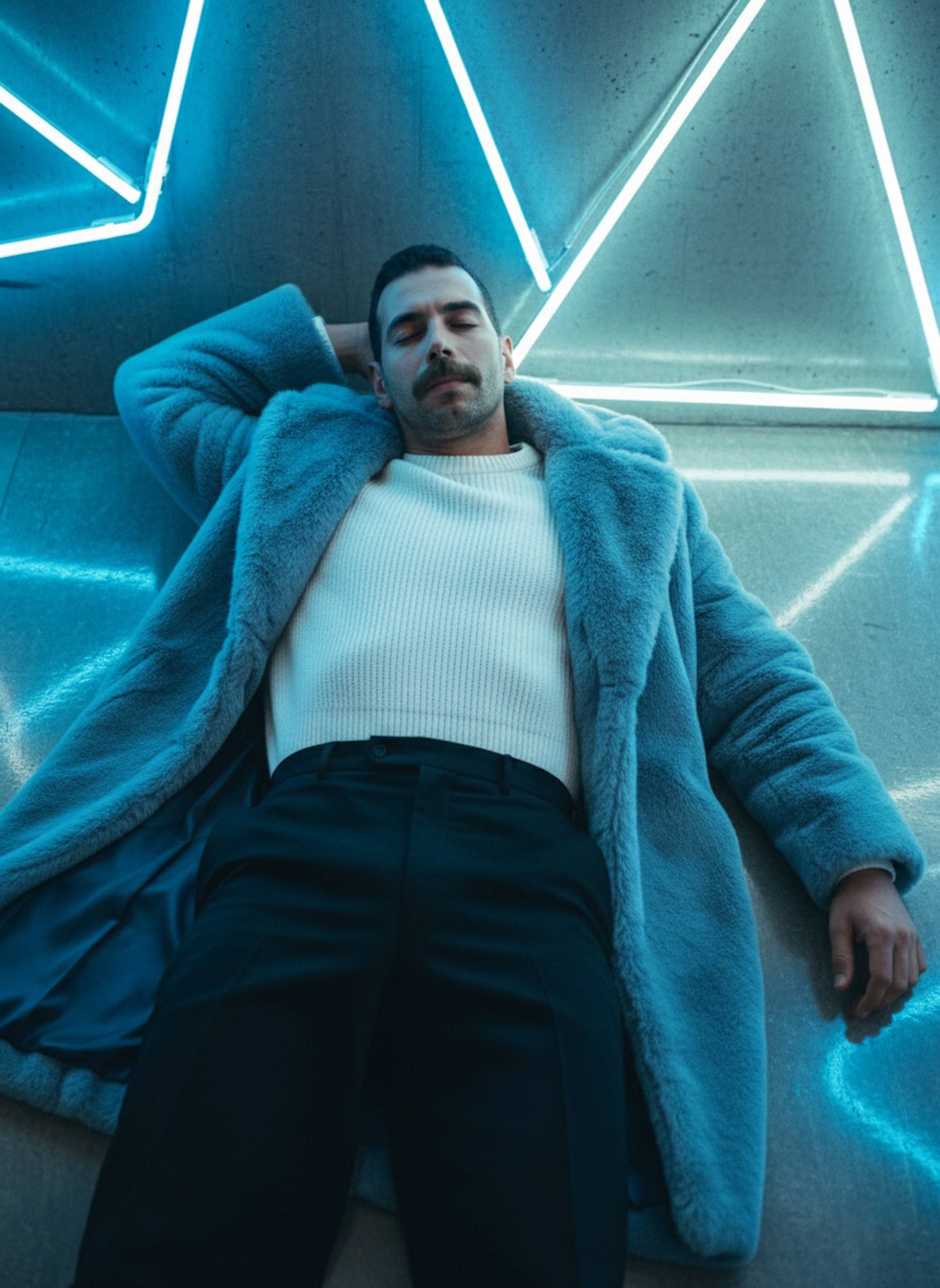 Person in light blue fur coat reclining on the floor against a bright blue and white neon wall